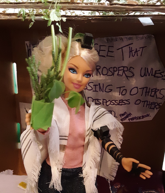 Very blonde Barbie holds homemade lulav in her sukkah